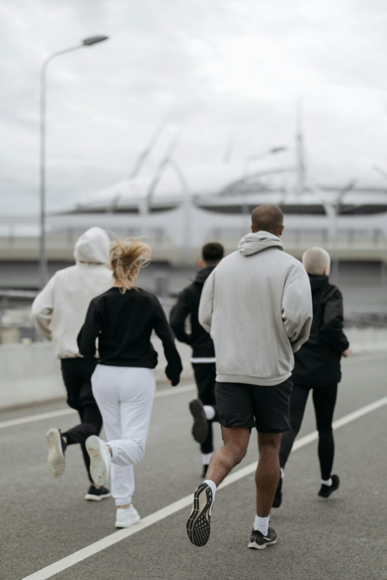 Five adults jogging outdoors in an urban area, promoting fitness and teamwork.